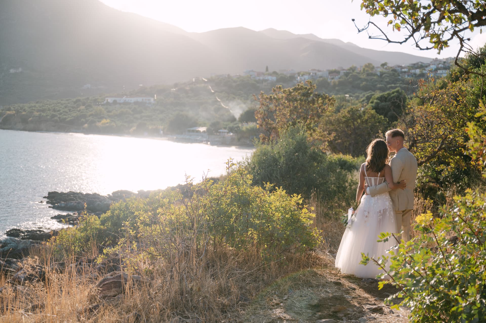 A couple embracing on a hill above the bay at sunset