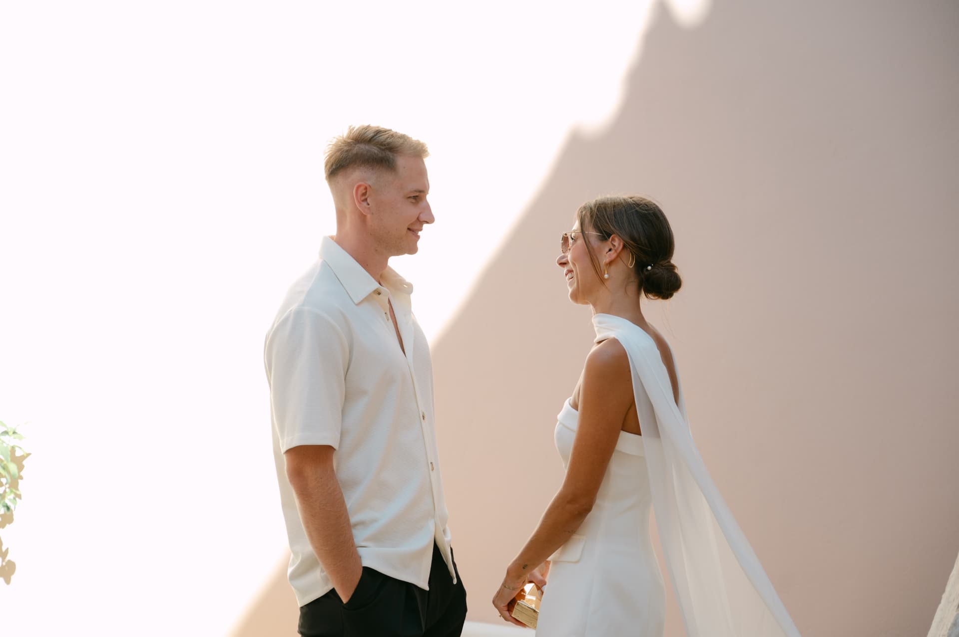 A bride and groom looking at each other in front of a warm-toned wall